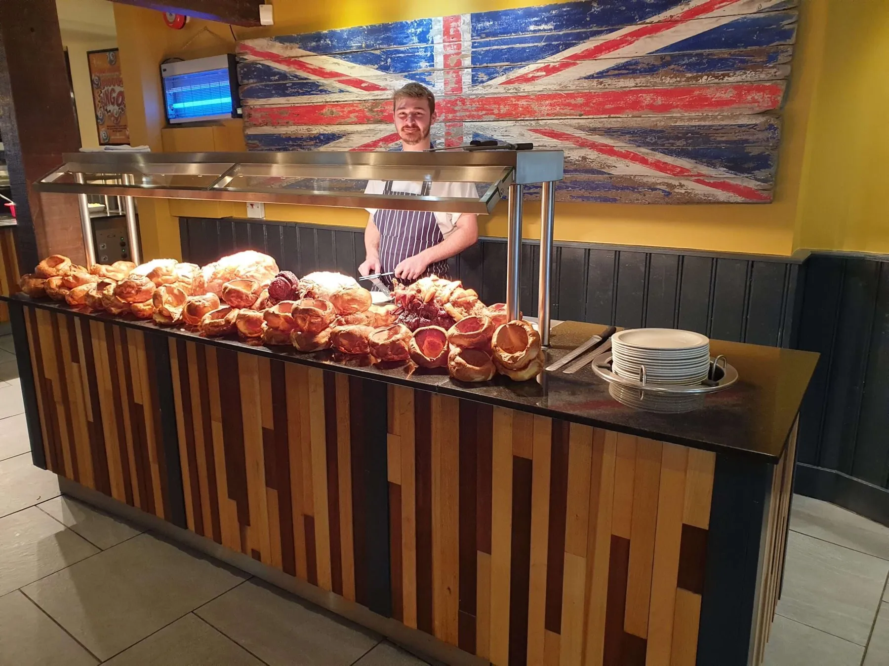 The carvery counter at The Nags Head, with the chef behind rows of Yorkshire puddings and roast joints