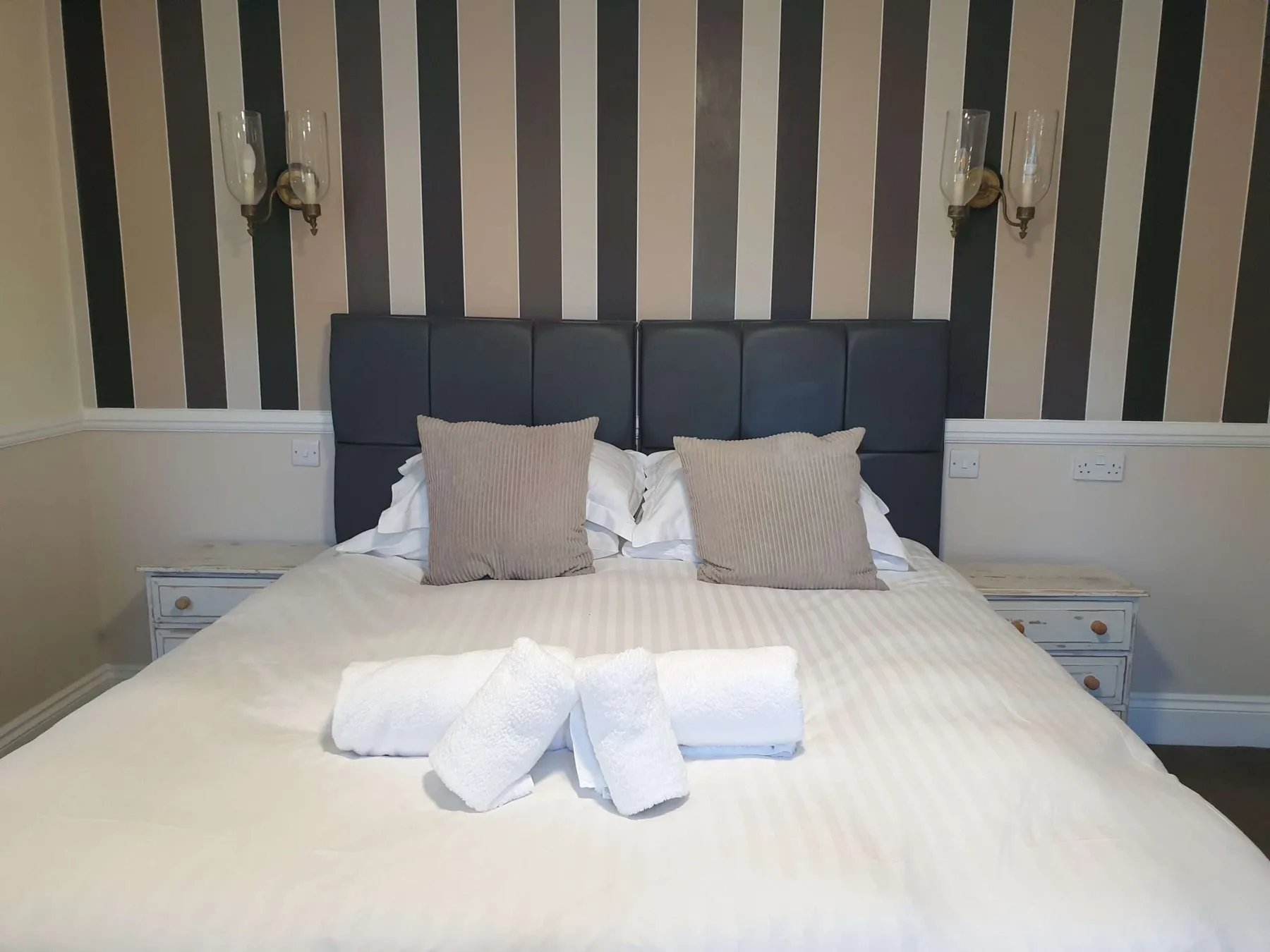A king-size bed with cushions and towels in a Nags Head hotel room